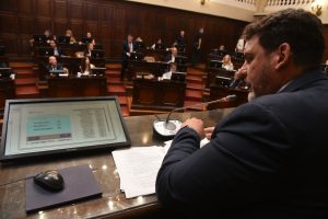 El nuevo régimen se adecua a la Ley Nacional de Inversiones Mineras, introduce un esquema progresivo de alícuotas y crea un fondo para desarrollo económico y socioambiental. El Senado provincial otorgó sanción definitiva al proyecto de Ley del Poder Ejecutivo que establece el régimen jurídico para la percepción de regalías mineras derivadas de la explotación de los recursos minerales en la provincia. Durante la votación, la propuesta fue aprobada por 30 votos a favor y 6 en contra. La iniciativa, que se adecúa a la Ley Nacional 24.196 de Inversiones Mineras y a la adhesión provincial vigente, define cómo se calculan y controlan las regalías mineras, garantiza trazabilidad y responsabilidad ambiental en toda la cadena productiva y establece que una parte de los fondos se destinará a los municipios que adhieran al régimen. El proyecto El objetivo de la propuesta es establecer el régimen jurídico aplicable a la percepción, determinación, liquidación, control, distribución y destino de las regalías mineras generadas por la explotación de recursos minerales en la provincia, conforme a los principios de la legislación vigente. La norma determina que la extracción de sustancias minerales de primera y segunda categoría —según los artículos 3 y 4 del Código de Minería de la Nación— queda sujeta al pago de regalías. El decreto reglamentario definirá el momento en que nace la obligación de pago, de acuerdo con la naturaleza de cada explotación. El régimen alcanza a todas las personas humanas o jurídicas, públicas o privadas, nacionales o extranjeras, que “en ejercicio principal o accesorio de su actividad, exploten, industrialicen y/o comercialicen minerales de primera y segunda categoría otorgados por el Estado provincial”. En los casos en que haya dos o más titulares, todos serán solidariamente responsables del pago total de la regalía. Quedan exceptuadas las empresas consideradas microempresas, según la definición de la Autoridad de Aplicación Nacional (Ley 25.300), y la extracción de sustancias minerales destinadas a investigación o con fines científicos o culturales. Monto y modalidad de las regalías Las regalías se determinarán aplicando los porcentajes establecidos sobre el valor “boca mina”, conforme a la Ley 24.196 y su reglamentación. La alícuota general será del 3% del valor del mineral. Para los proyectos que no hayan iniciado la construcción de la etapa de explotación antes de la entrada en vigencia de la Ley, se prevé una alícuota progresiva y móvil, que no podrá superar el 5%, según establezca la reglamentación. La norma también contempla reducciones, exenciones parciales y regímenes diferenciales para promover proyectos con agregado de valor local, tecnologías limpias, obras de infraestructura con impacto social, o cumplimiento de estándares ambientales y de inclusión social y de género. Distribución de los recursos El proyecto establece que: - 88% de la recaudación se destinará a Rentas Generales. De ese monto, el 15% será afectado al Fondo de Desarrollo Económico y Socioambiental, creado por esta Ley. Este Fondo financiará proyectos de desarrollo económico, social, productivo y territorial; obras e infraestructuras socioambientales vinculadas a la actividad minera; así como acciones de control, monitoreo, participación ciudadana y fortalecimiento institucional. Podrá administrarse mediante un fideicomiso u otra figura legal idónea. - El 12% restante se asignará a los municipios donde se realice la extracción, siempre que adhieran al régimen. Estos recursos deberán destinarse exclusivamente a obras públicas y a infraestructura económica, social, ambiental y productiva. Fundamentación La fundamentación del proyecto sostiene que la propuesta “establece un régimen claro, equitativo y transparente de determinación y percepción de regalías mineras”, asegurando la adecuada participación provincial y municipal en la renta de la actividad. También remarca que los recursos asignados permitirán fortalecer el control ambiental, promover el desarrollo local y mejorar la capacidad institucional. Además, se destaca que esta Ley provincial moderna “aporta certeza regulatoria, mejora la calidad institucional y favorece la atracción de inversiones responsables”, en consonancia con el régimen minero vigente. Finalmente, el texto subraya que el fortalecimiento de los estándares de trazabilidad y control es clave para sostener la licencia social y garantizar previsibilidad a lo largo del ciclo de vida de los proyectos.